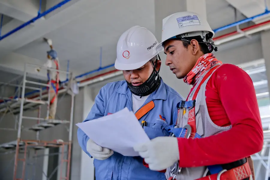Dos técnicos con casco revisando planos en obra